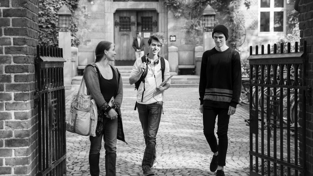 3 studenter på väg ut genom en grind